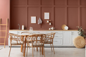 Interior of stylish kitchen with dining table and white counters near brown wall
