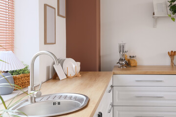 Interior of stylish kitchen with counters, sink and utensils