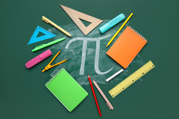 Number Pi and school stationery on green chalkboard, closeup