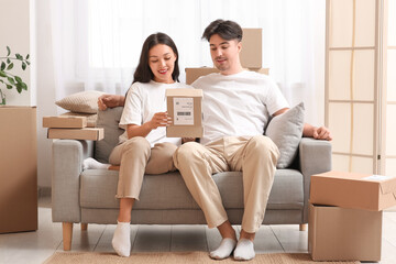Young couple unpacking parcel box on sofa at home