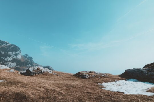Mountain vista, dry grass, snow patches, clear sky - Powered by Adobe