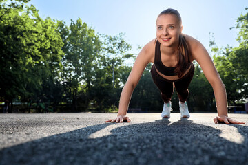 Sporty young woman doing plank in park