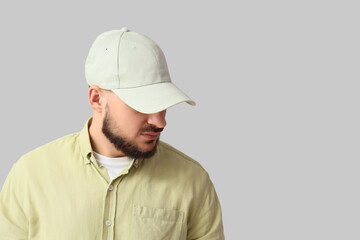 Handsome young man in stylish cap on grey background