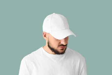 Handsome young man in stylish cap on blue background