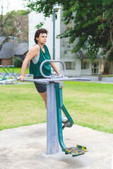 Fototapeta premium Young woman exercising her legs on an outdoor fitness station with effort