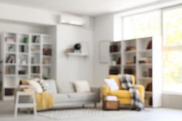Blurred view of stylish living room with yellow armchair, grey sofa and bookshelf