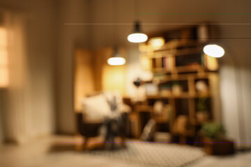 Blurred view of stylish living room with grey armchair, glowing lamps and bookshelves at evening