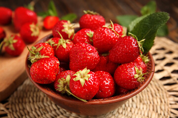 Bowl with sweet ripe strawberries and mint leaf on wooden background, closeup