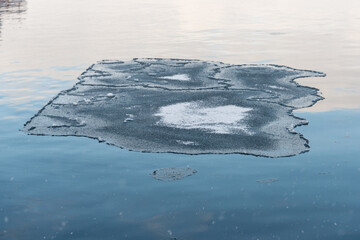 A large ice surface with odd-shaped cracks or frazil ice in a harbor. The cold winter temperatures have formed pan-shaped formations, rotational shears, or ice discs. The joins are crystal frost spots
