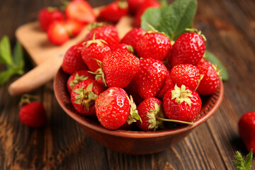 Bowl with sweet ripe strawberries and mint leaf on wooden background, closeup