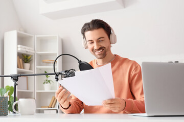 Male radio presenter with papers recording in studio