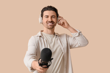 Male radio presenter in headphones with microphone on beige background