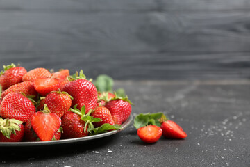 Plate with sweet ripe strawberries on black table