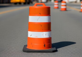Orange traffic barrel with white reflective stripes on asphalt road cone safety
