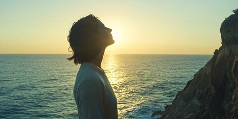 A coastal cliff where a person stands with eyes closed, enjoying the rhythmic sound of the ocean