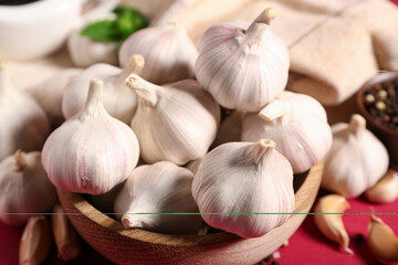 Wooden bowl with fresh garlics on red background, closeup