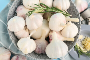 Bowl with fresh garlics and rosemary on blue background
