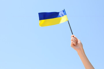 Woman holding flag of Ukraine on blue sky background