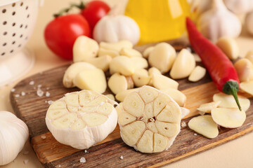 Wooden board with fresh garlics and chili pepper on beige background, closeup