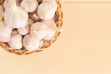 Wicker bowl with fresh garlics on beige background