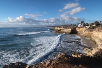 Obraz premium Coastal scene of ocean waves crashing against a rocky shore, with a line of buildings on the cliffs above
