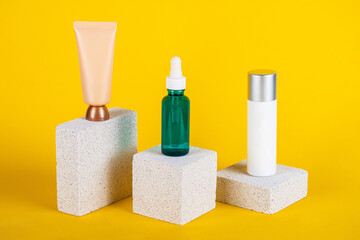 Plastic white tube for cream or lotion set. Skin care or sunscreen cosmetic with stylish props on yellow background.