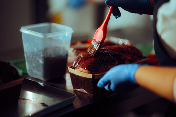 Pastry Chef Brushes Chocolate on Traditional Cozonac Cake. A confectionery worker puts a layer of chocolate on a cake
