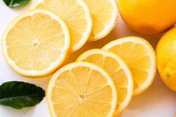 A vibrant close-up of translucent lemon slices, revealing their juicy texture and bright yellow color, with a hint of two whole lemons in the background.