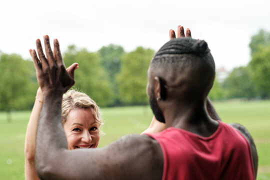 Personal trainer and client giving high five after successful workout in park