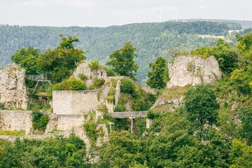 Fototapeta premium Ruins of a medieval castle surrounded by lush greenery in a hilly landscape