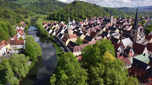 Fly toric riverside town surrounded rolling hills church steeples colorful rooftops spring foliage glow 4K detail beautiful mix sun and