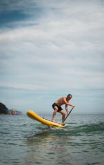 Athletic male balancing on paddleboard, enjoying summer vacation on ocean waves. Perfect expression of sunny freedom, physical action and joyful lifestyle. Sup board