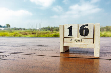 Wooden cube calendar for 16th August place on a table in a sunny day background