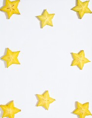 Vibrant starfruit slices arranged artistically on a clean white background with natural light casting shadows