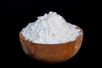 white flour in a wooden bowl isolated on black background