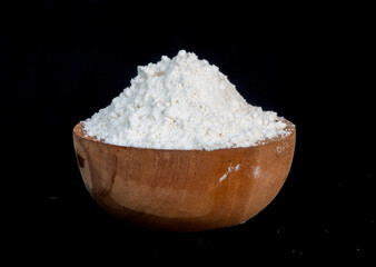 flour in a wooden bowl with a black background