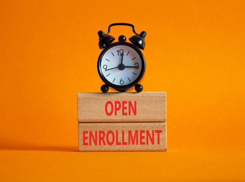 Open Enrollment symbol. Wooden blocks with words Open Enrollment. Beautiful orange background with alarm clock. Business and Open Enrollment concept. Copy space.