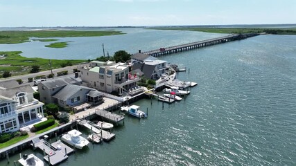 Luxury beach houses with bay view and bridge in stone harbor beach, New Jersey. Sunny day with marshland in background. Private access and jetty with docking boats.