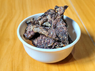 Fried beef lung with flour, has a delicious and delicious taste, served in a white bowl on a wooden table.