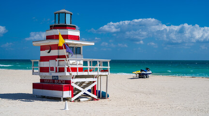 Fototapeta premium Miami Beach lifeguard at the summer beach. South Miami Beach with lifeguard. Sky above lifeguard tower in Miami. Iconic lifeguard tower on sand in Miami. A symbol of Miamis coast.