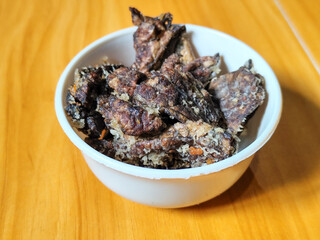 Fried beef lung with flour, has a delicious and delicious taste, served in a white bowl on a wooden table.
