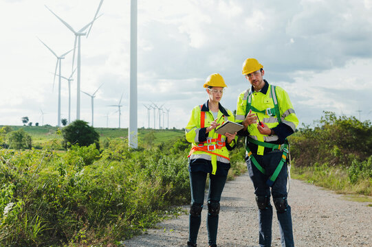 Two workers in safety gear are looking at  clipboard