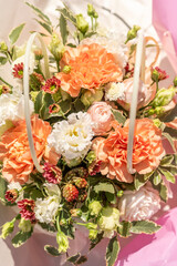 Romantic flower basket with peach roses, white carnations, burgundy daisies, and unripe blackberries. Natural and tender floral arrangement, perfect for gifting or decoration. Shot in sunlight.