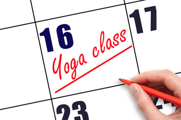 16th day of the month.  Hand writing Yoga class reminder and drawing a line on calendar with red pen on white background. Concept of sport and fitness activity.  Planning and scheduling