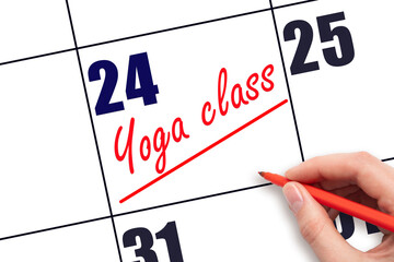 24th day of the month.  Hand writing Yoga class reminder and drawing a line on calendar with red pen on white background. Concept of sport and fitness activity.  Planning and scheduling