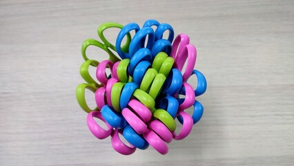 Top view of a bundle of colorful safety scissors with plastic handles in pink, blue, and green,...