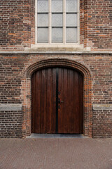 Arched wooden doors set in a brick facade with a window above, a classic architectural detail.