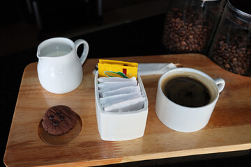 black coffee in the white cup on the wood tray with beans in the jar