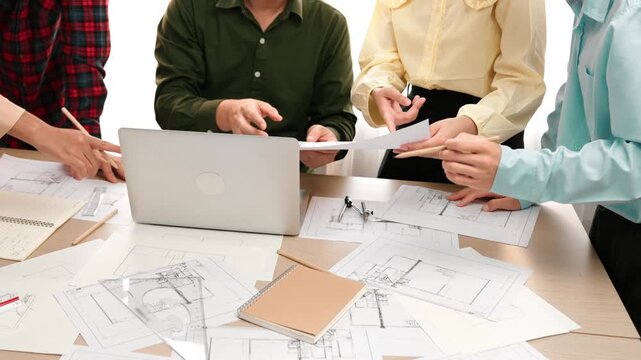 Smart architect and safety engineer discussion about building plan on table with architectural document, measurement tools and wooden block scatter around at modern office. Closeup. Delineation.