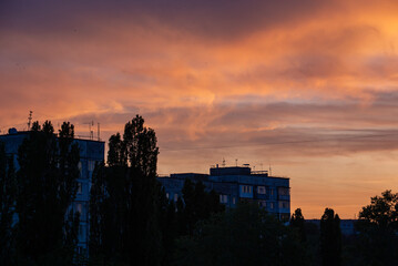 Fototapeta premium Sunset over Soviet-era apartment buildings and trees 